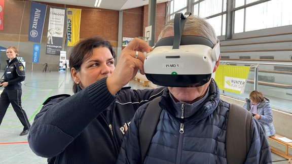 Ein Mann bekommt eine VR-Brille aufgesetzt.