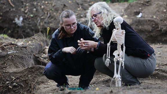 Richtstätten-Achäologin Marita Genesis (r.) erklärt Studentin Romy Wirsich Knochenfunde auf einer historischen Richtstätte im Harz.