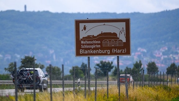Ein touristisches Hinweisschild mit der Aufschrift "Welfenschloss Schlossgärten Blankenburg (Harz)" steht am Rande einer Autobahn