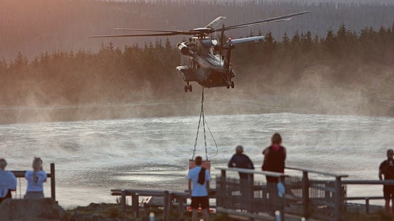 Ein Hubschrauber der Bundeswehr nimmt am Rückhaltebecken am Torfhaus Wasser für die Waldbrandbekämpfung.