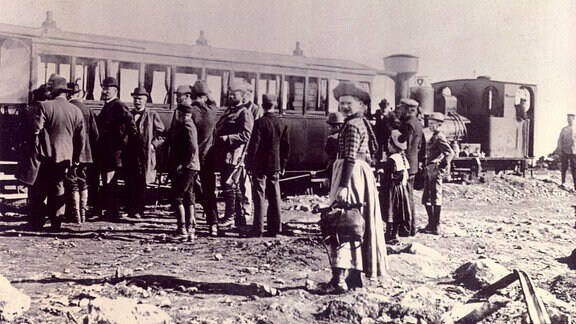 Ein historisches Foto mit Menschen, die vor einem Zug stehen