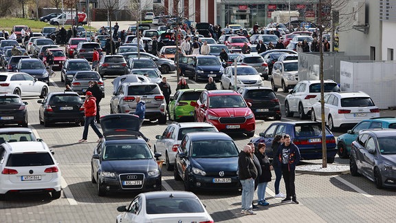 Fans der Tuningszene stehen mit ihren Autos auf einem Parkplatz in Blankenburg