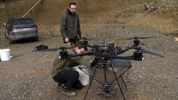 Zwei Männer an Drohne in Wald