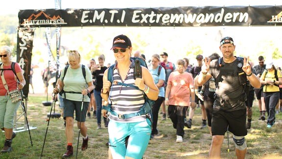 Menschen in Sportkleidung laufen durch ein Schild, auf dem "Extremwandern Harz" steht