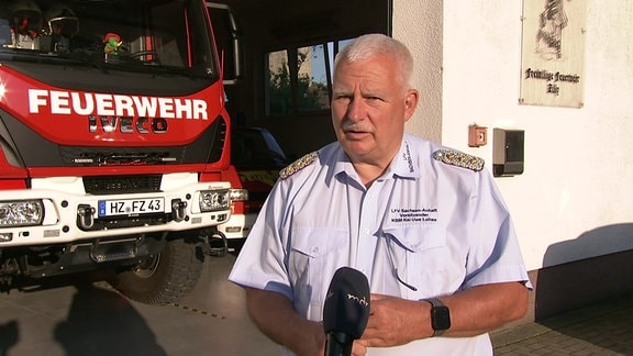 Kai-Uwe Lohse steht vor einem Feuerwehrauto.