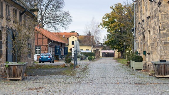 Rechts und links eines gepflasterten Weges stehen alte Gebäude.