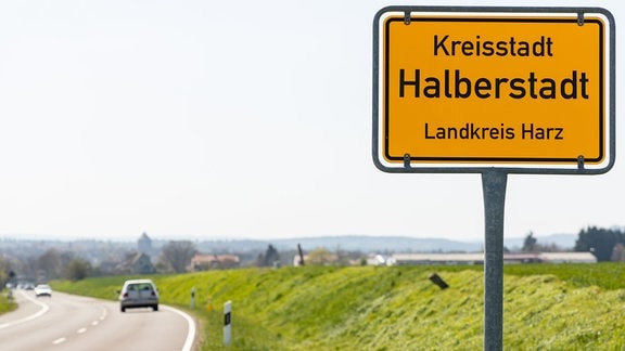 Neben einer Straße steht ein Ortsschild von Halberstadt.