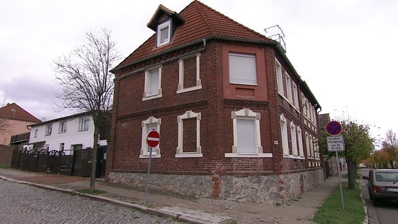Ein ziegelrotes, zweistöckiges Haus mit weiß gerahmten Fenstern