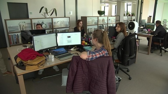 Menschen an Computern in einem Großraumbüro