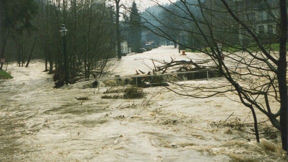 Eine Straße ist überschwemmt mit Wassermassen, das Bild sieht alt und analog aus