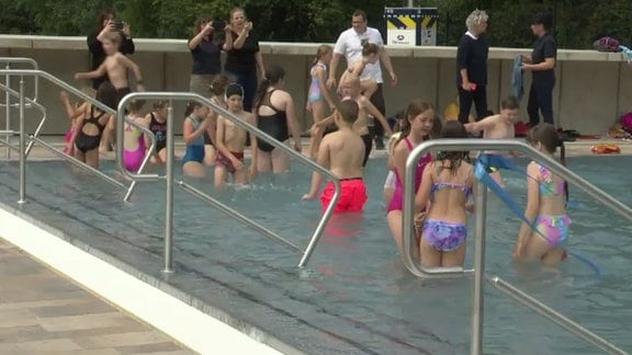 Kinder springen ins neu eröffnete Schwimmbad von Quedlinburg.