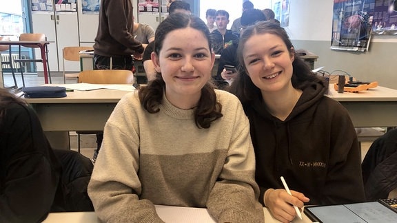 Die Schülerin Laura Heinemann (links) sitzt neben einer Freundin an einem Tisch in der Schule.