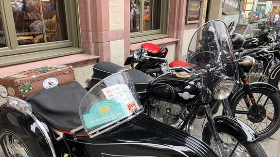 Schwarzes Oldtimer-Motorrad in einer Reihe anderer Zweiräder