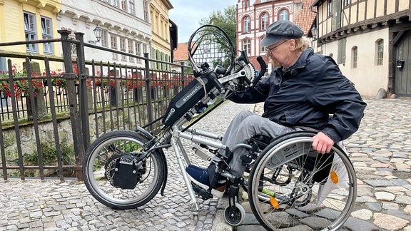 Ein Mann im Rollstuhl fährt einen Bordstein hoch.