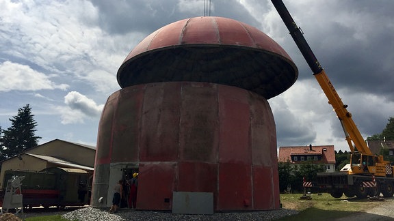 Dach einer Kuppel wird mit einem Kran auf den Unterbau gesetzt