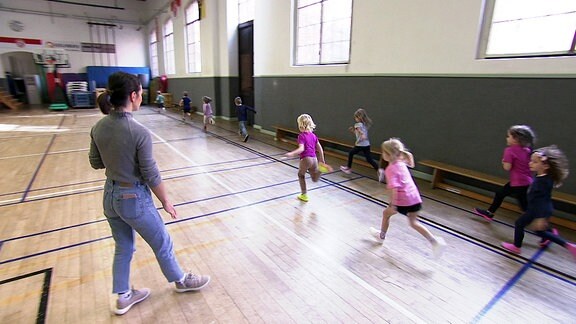 Kinder rennen durch Turnhalle.