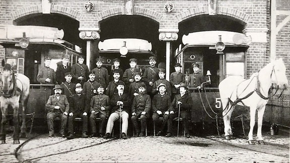 Historische Archivaufnahme: Männergruppe vor einem Straßenbahndepot