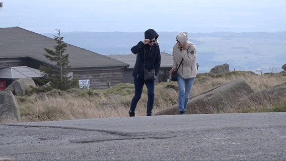 Zwei Wanderinnen kämpfen sich durch den Sturm auf dem Brocken.