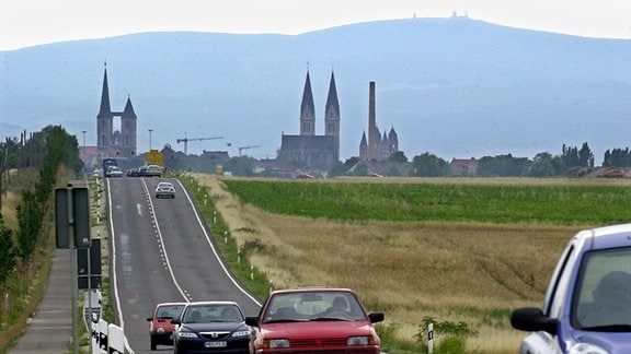 Durch ein Teleobjektiv betrachtet scheint die Stadt Halberstadt direkt am Fuße des Brockens zu liegen. Im Vordergrund die Bundesstraße 81, die direkt zur Martinikirche (l) zu führen scheint, in der Mitte der Halberstädter Dom.