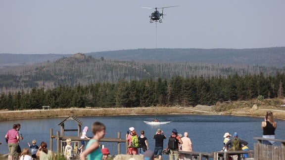 Ein Hubschrauber nimmt am Rückhaltebecken am Torfhaus Wasser für die Waldbrandbekämpfung am Brocken auf. 