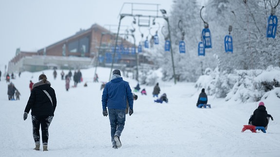 Wintersportler sind am Rodellift "Brockenblick" auf einer Schlittelpiste unterwegs.