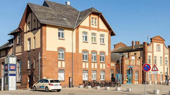 Gebäude des Bahnhofs Burg, im Vordergrund steht ein Taxi