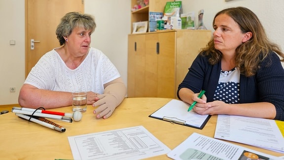 Daniela Schmidt und Bianca Hoffmann (l.) und eine psychoonkologische Beraterin an einem Tisch im Gespräch