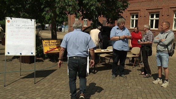 Menschen auf dem Marktplatz in Genthin sammeln Wünsche zur medizinischen Versorgung in der Stadt