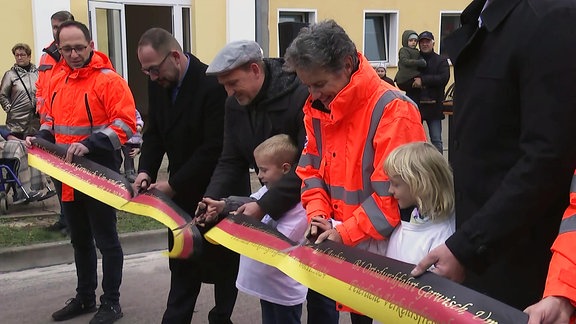 Menschen schneiden eine Banderole an der B1 in Gerwisch durch