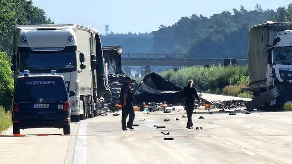 Mitarbeiter der Polizei gehen auf der Autobahn 2 zwischen Theeßen und Burg zu einer Unfallstelle
