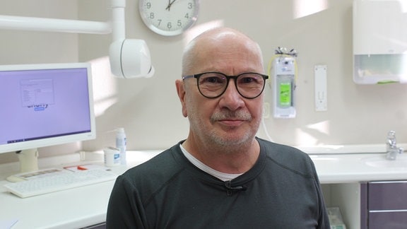 Zahnarzt mit Dreitagebart, Glatze und dunkler Brille im Porträt