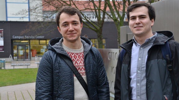 Zwei junge Männer vor einem Gebäude auf dem Uni-Campus der OVGU in Magdeburg