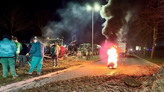 Landwirte blockieren mit Mist und brennenden Reifen eine Straße bei Magdeburg.