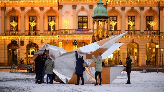 Bürger der Stadt Magdeburg und Mitarbeiter der Arbeiterwohlfahrt (AWO) stellen auf dem Alten Markt vor dem Rathaus eine XXL-Friedenstaube aus Milchtütenkarton auf.