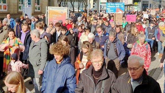 Demonstranten laufen vor dem City-Caré in Magdeburg einen Weg entlang. 