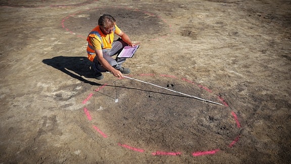 Der Archäologe Nikita Sirman vom Landesamt für Denkmalpflege und Archäologie vermisst und kartiert den Grundriss eines Hauses.