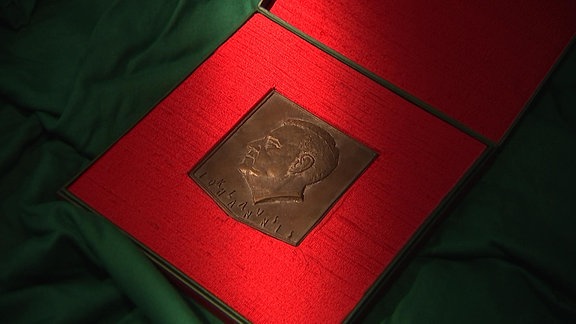 Eine Medaille liegt auf einem roten Tuch.