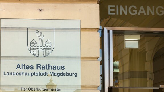 Ein Plexiglasschild neben einer Eingangstür weist auf das Alte Rathaus in Magdeburg hin. 