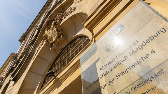 Ein Schild aus Plexiglas hängt an einem Gebäude in Magdeburg.
