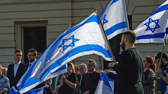 Teilnehmer einer Solidaritätskundgebung für Israel halten die Fahne Israels in den Händen. 