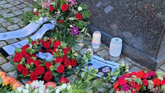 Blumen, Kränze und ein Bild liegen im Gedenken an Ella auf dem Friedensplatz in Magdeburg.