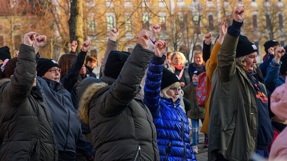 Teilnehmerinnen eines Tanz-Flashmops tanzen mit erhobenen Händen auf dem Domplatz von Magdeburg.