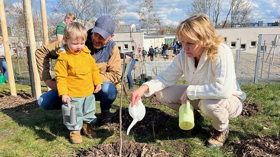 Steffi Lemke, Ministerin für Umwelt- und Naturschutz, wässert bei einer Pflanzung mit einem Kind einen Baum.