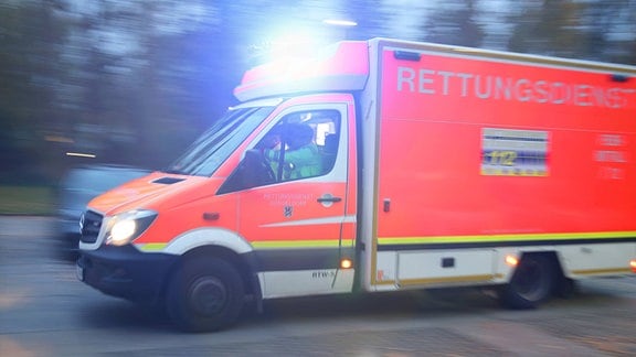 Ein Rettungswagen fährt mit Blaulicht durch eine Straße zum Einsatz.