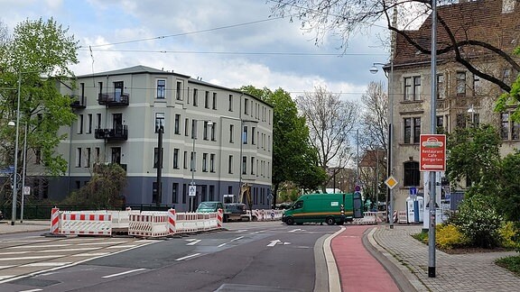 Blick auf eine gesperrte Straßenkreuzung mit einem grünen Baustellenfahrzeug.