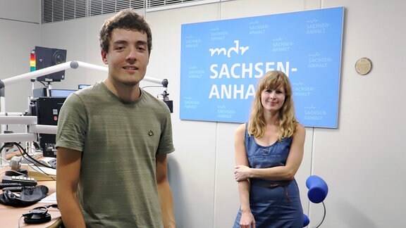 Junger Mann in grünem T-Shirt und Frau in blauem Kleid stehen mit Abstand voeinander im MDR SACHSEN-ANHALT-Radiostudio.