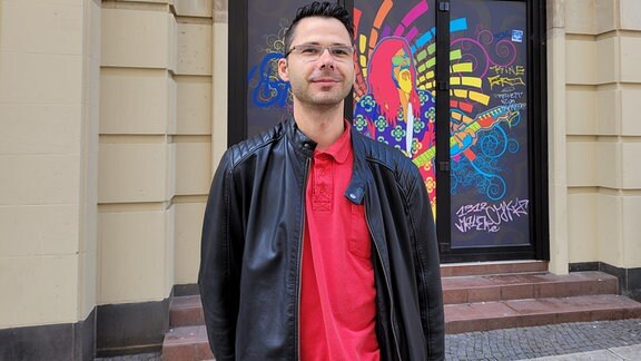 Ein Mann mit roterm T-Shirt und Lederjacke steht vor dem Flowerpower in Magdeburg.