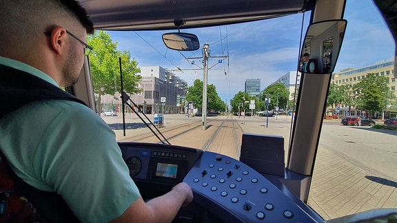 Blick über die Schulter eines Straßenbahnfahrers aus dem Cockpit.