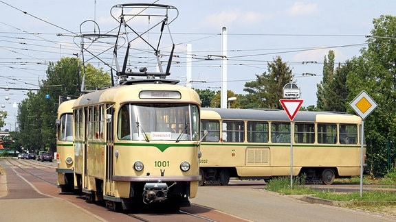 Der T4D Tatra-Triebwagen mit der Wagennummer 1001 fährt einen weiteren Triebwagen und einen Beiwagen um die Kurve eines Depots