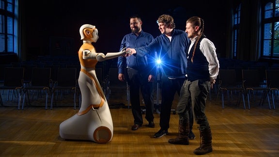 Matthias Busch (l-r), Ingo Siegert und Dominykas Strazdas vom Institut für Informations- und Kommunikationstechnik Fachgebiet Mobile Dialogsysteme an der Otto-von-Guericke-Universität reichen dem humanoiden Roboter «Ari» die Hand.